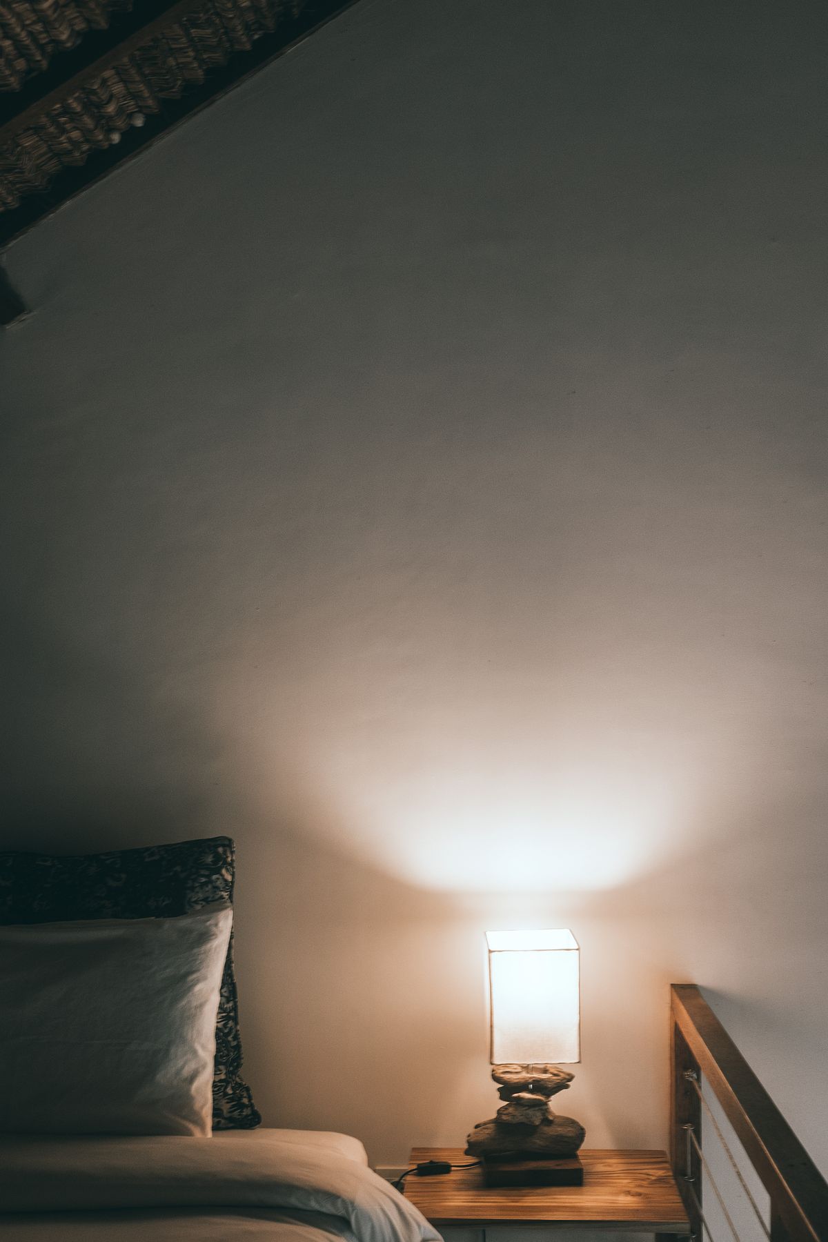 An illuminated lamp beside a bed