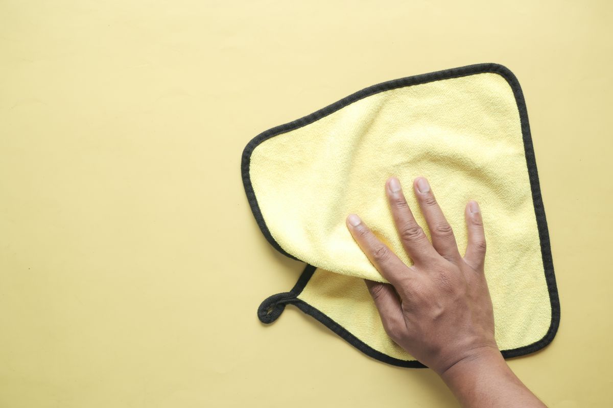Hand holding a yellow microfibre cloth