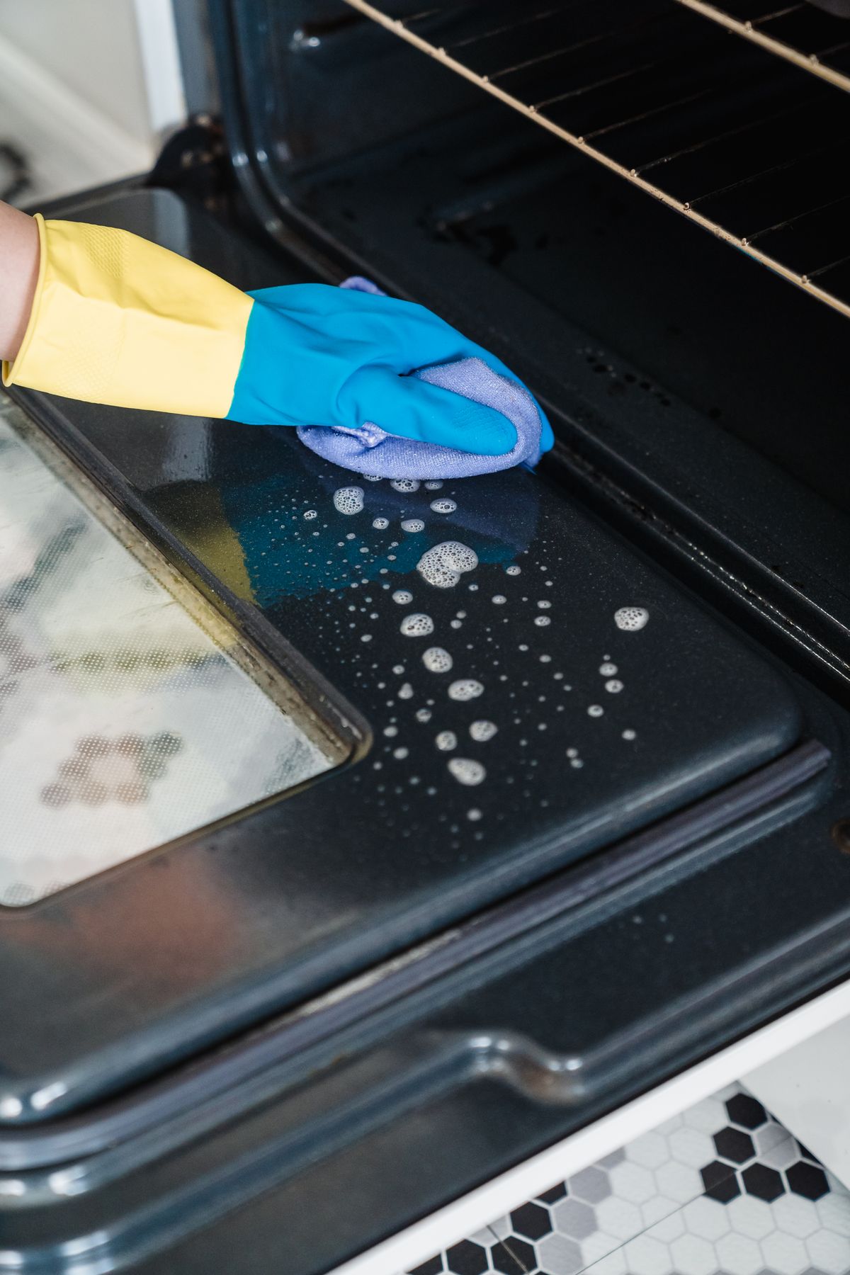 Cleaning an oven door while wearing gloves