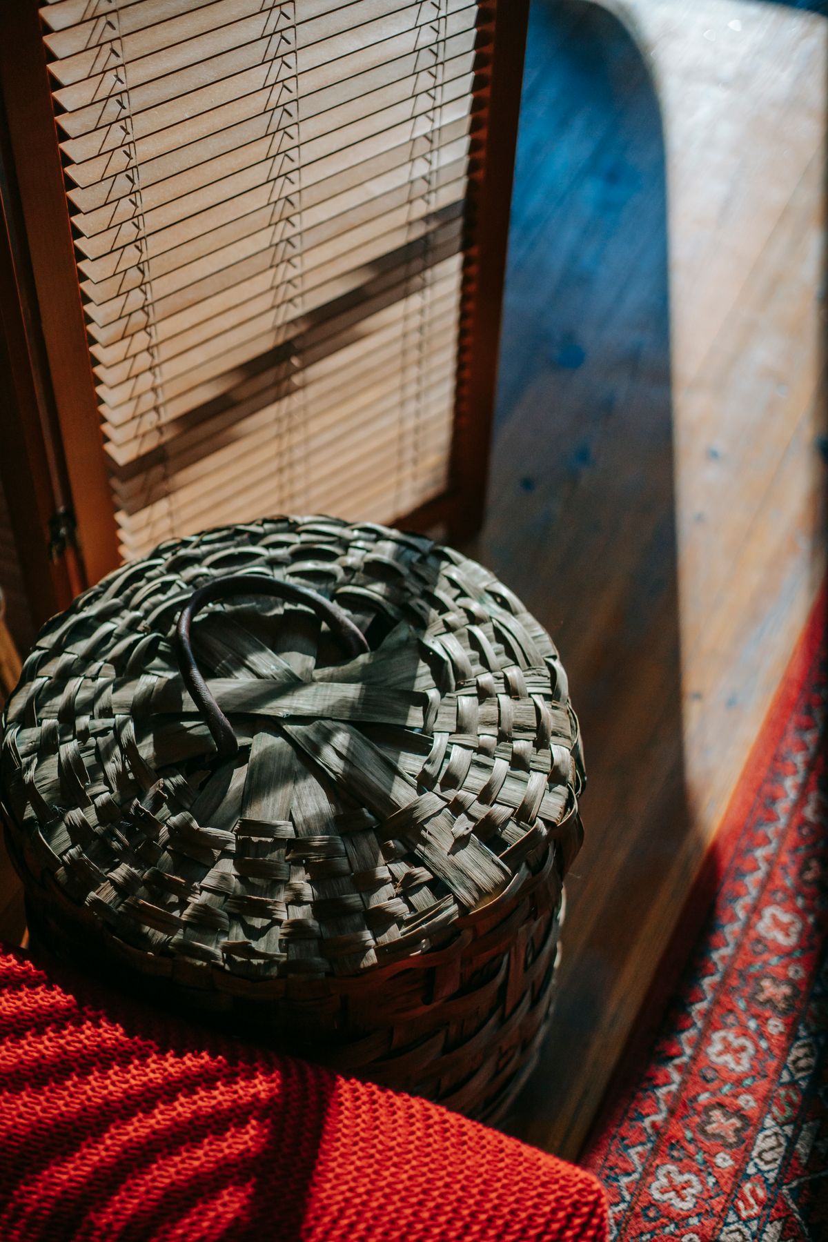 Woven fibre basket beside a red rug